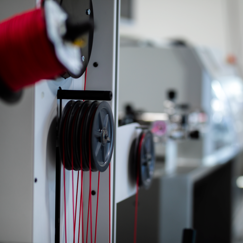 image of red wire on a kappa machine. Roll of wires in Precision Cables.