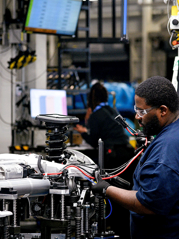 automotive wire harness being installed by a man wearing protective glasses. precision cables