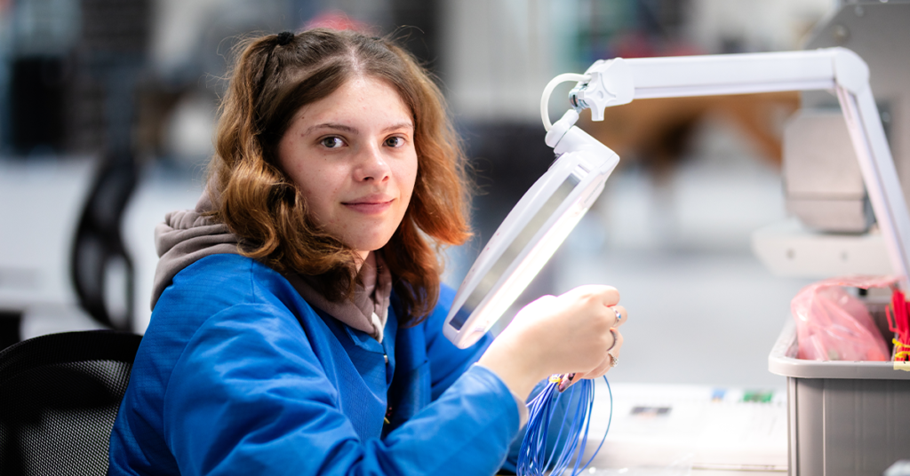 Image of a young girl quality inspector. Inspecting wires for a cable assembly.